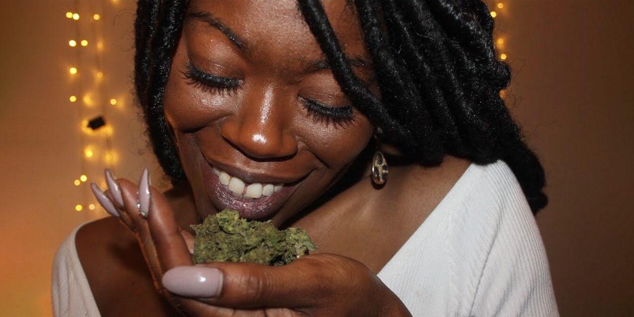 woman holding a cannabis on her hand close to her chin