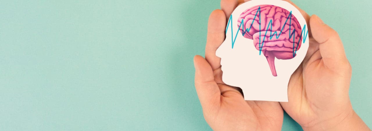 A person's hands holding a silhouette of a head with a brain