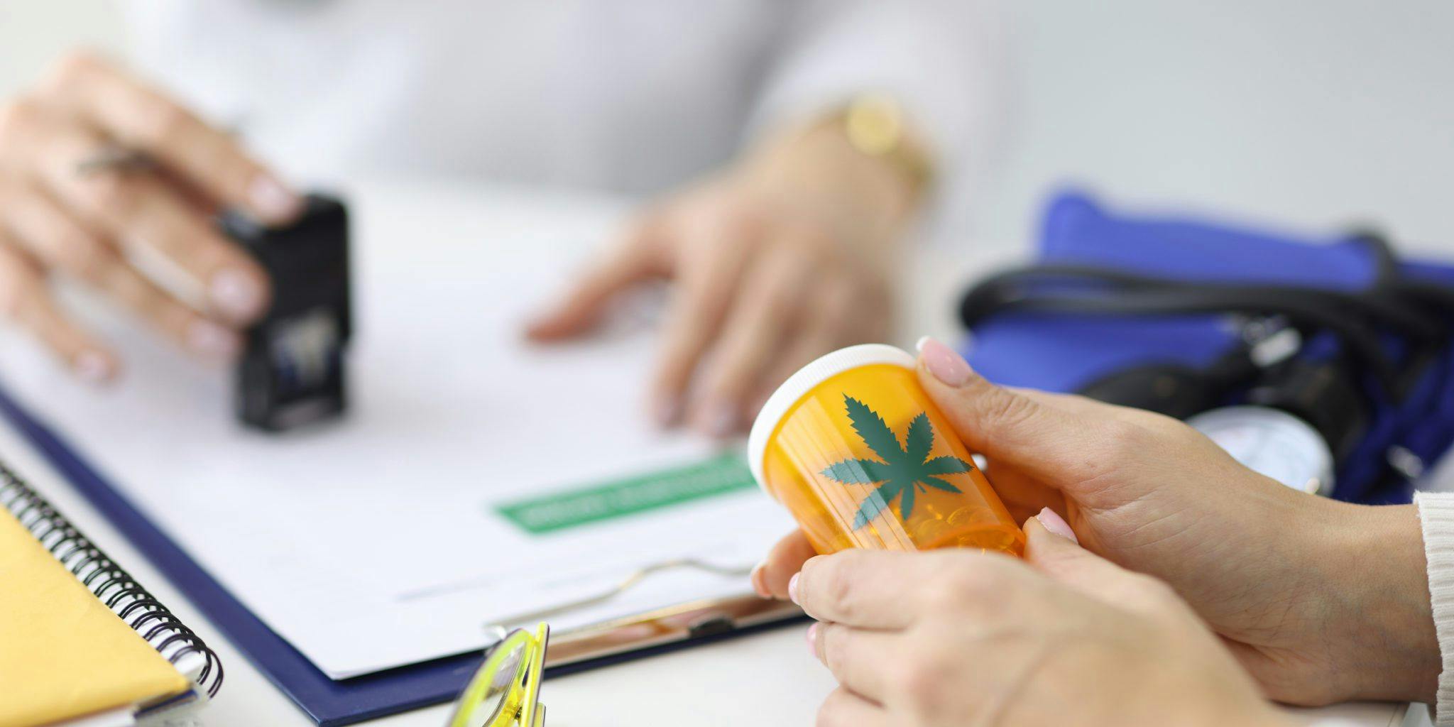 closeup woman holding medicine pill container with marijuana leaf as label