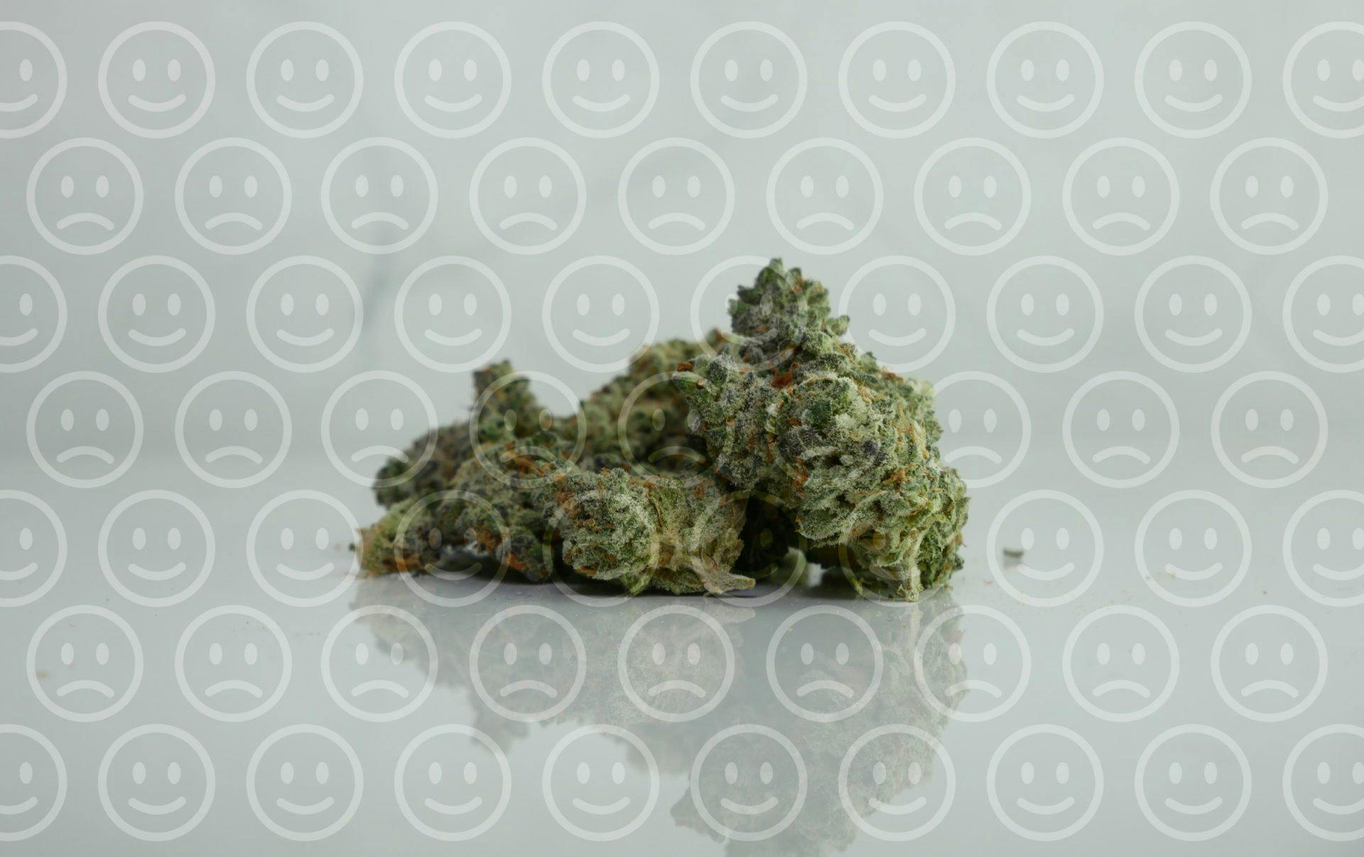 marijuana with sad and smiley emoticon as background