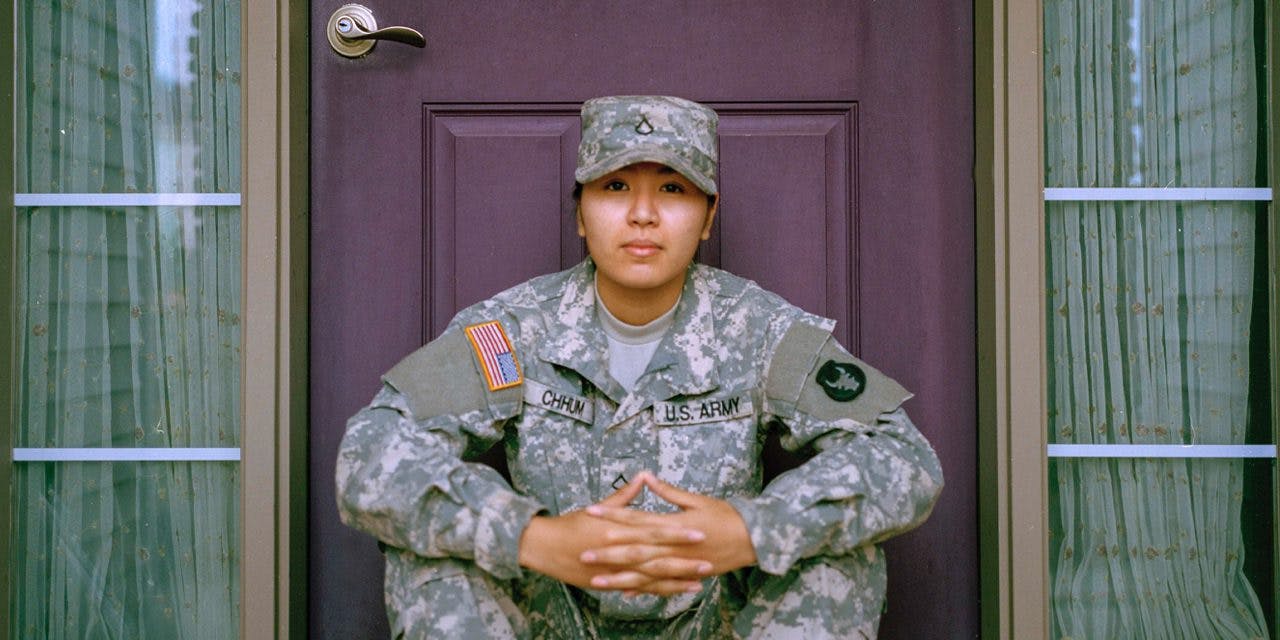 woman in military uniform seated in front of a door