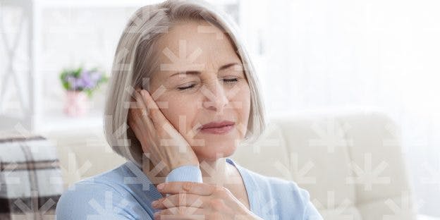 old woman touching her one side of the face while closing eyes