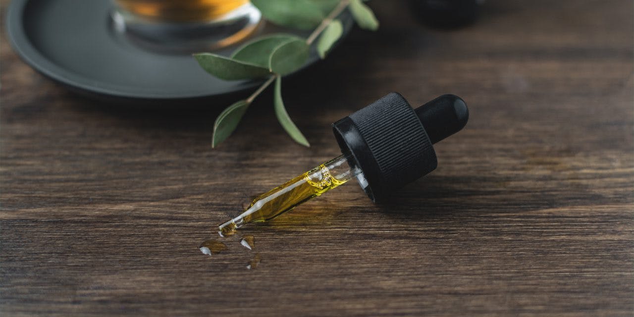CBD oil in a dropper lying on a wooden table