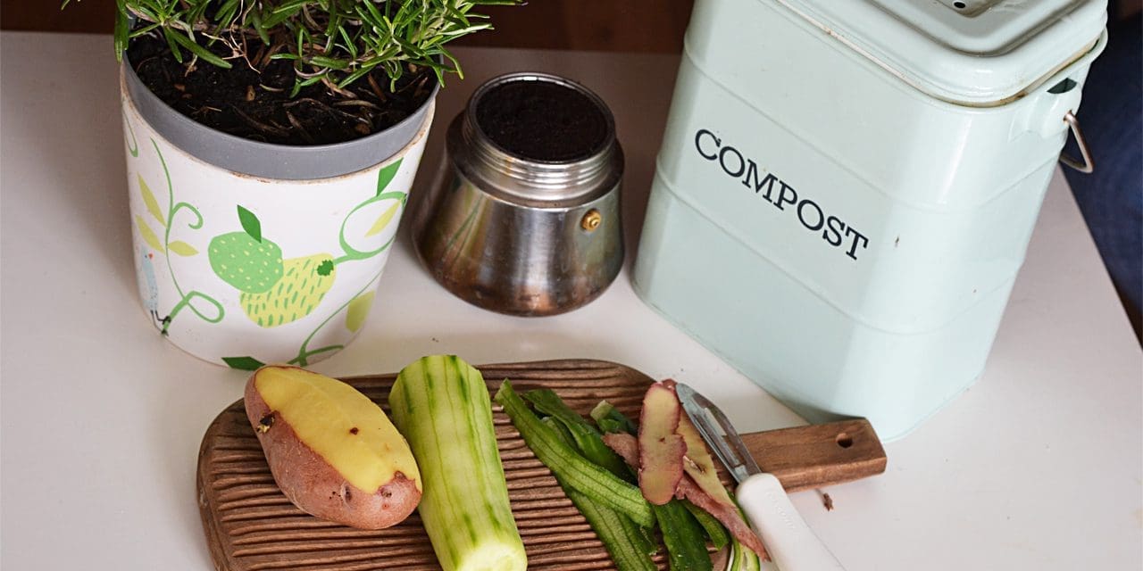 half-peeled vegetables next to a pot and a compost garbage can