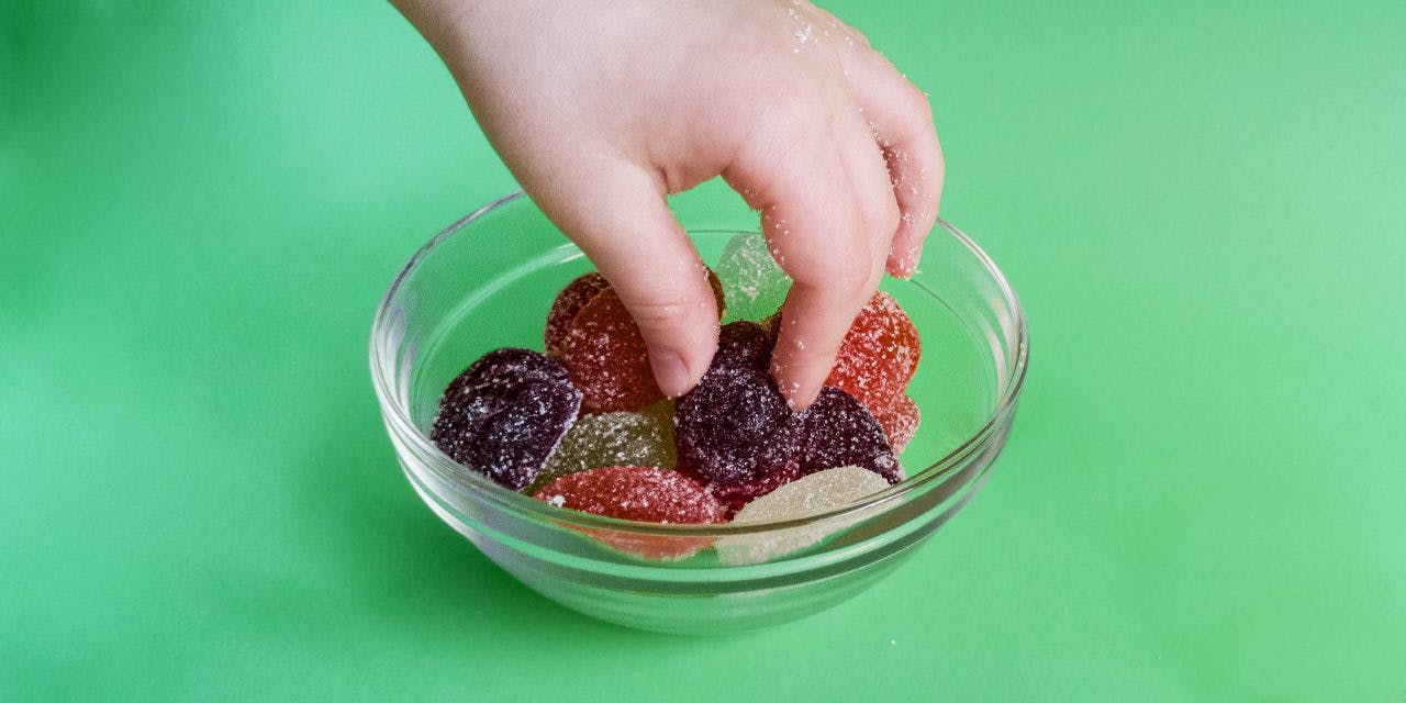 gummies in a clear bowl and child's hand picking them