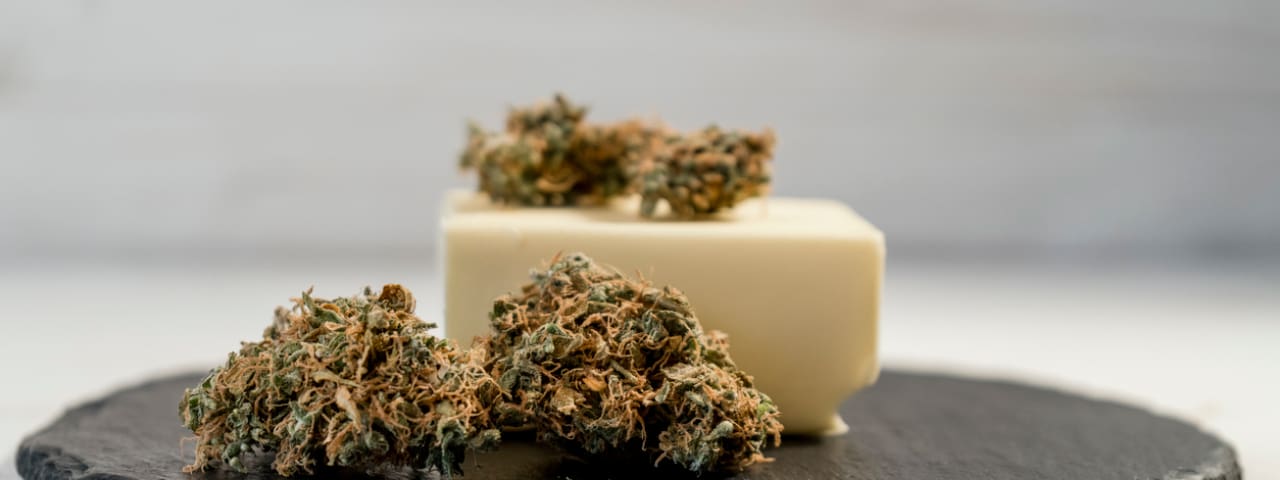 Butter and cannabis buds on a cutting board