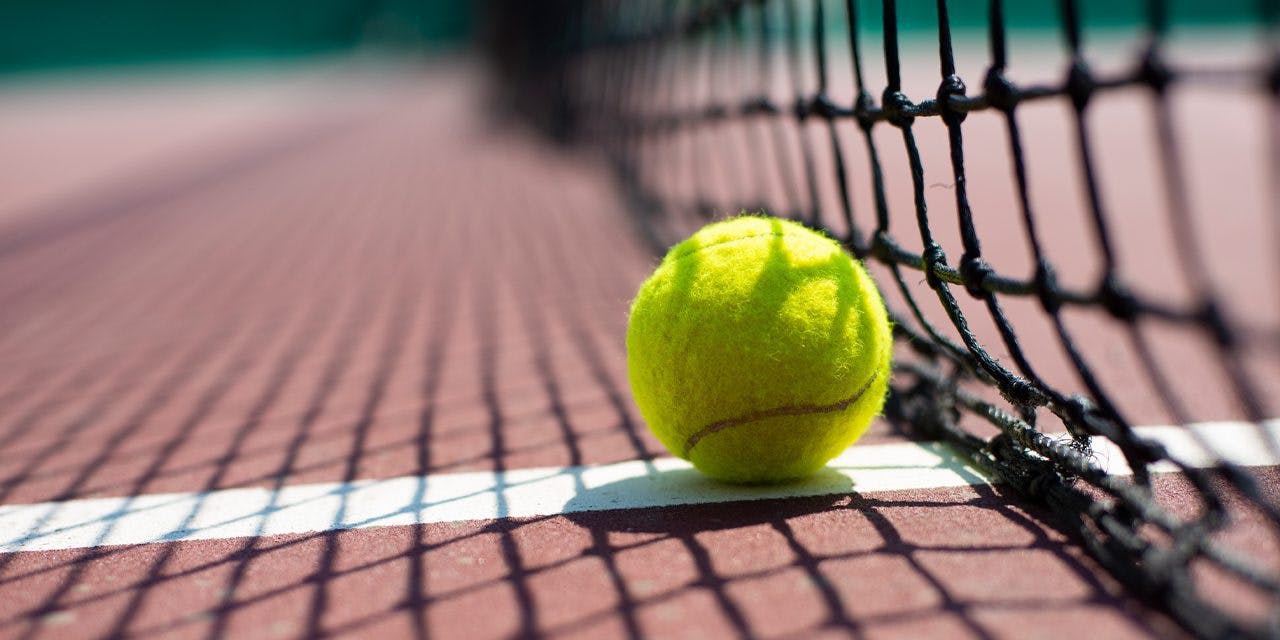 tennis ball on the ground beside the net