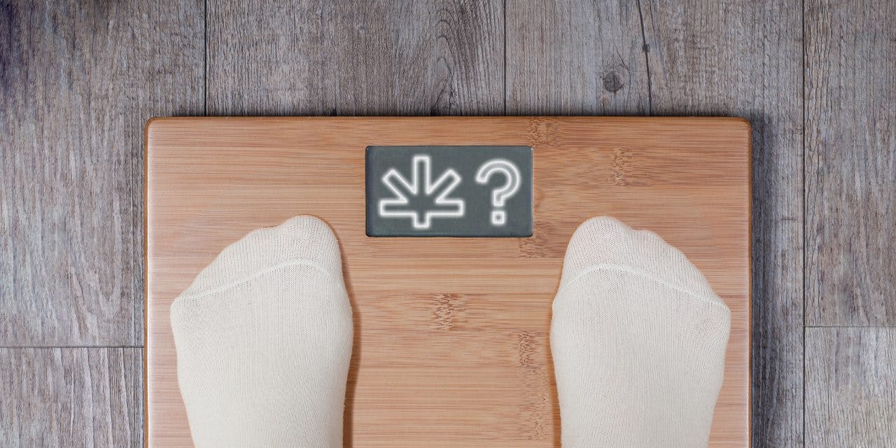closeup of feet on top of a wooden weighing scale with leafwell logo and question mark showing on screen
