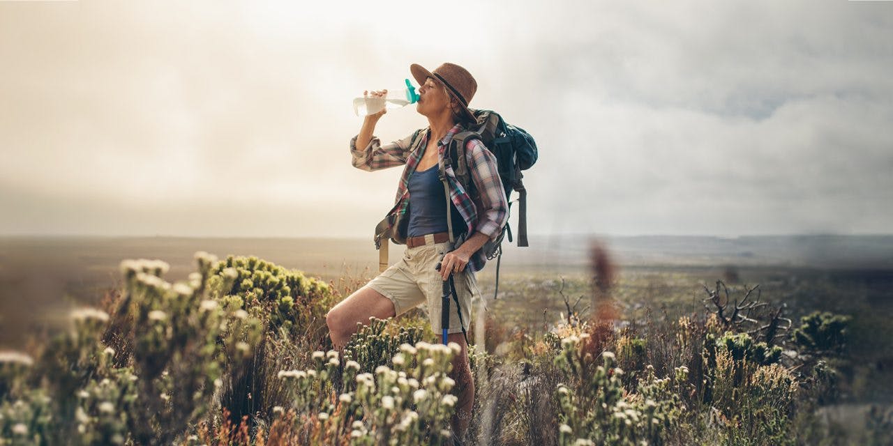 woman in a hiking attire drinking water