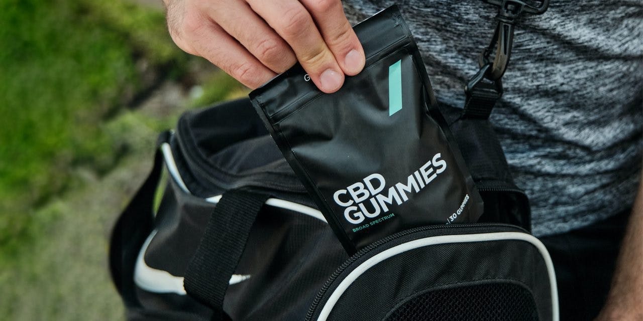 closeup of gym bag and a hand carrying a pack of CBD gummies
