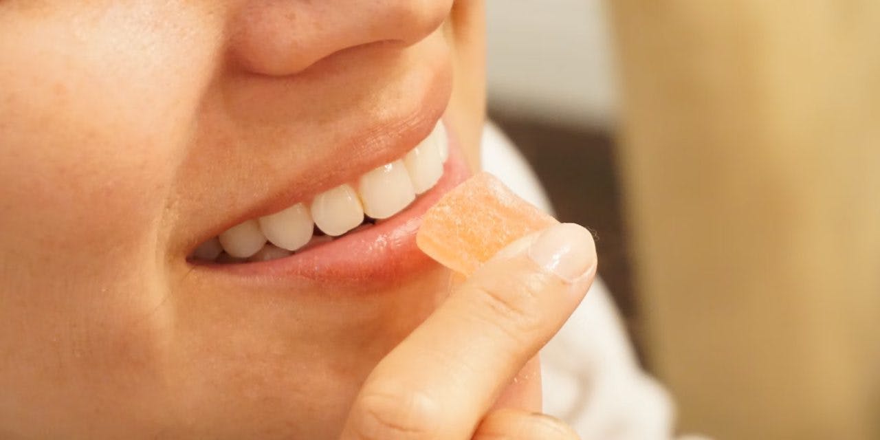 close up of smiling woman trying to eat gummy candy